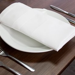 A white table set with silverware and white linen napkin