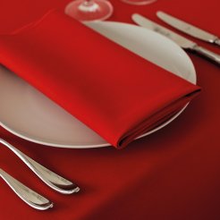 A white plate adorned with silverware and a vibrant red napkin neatly placed on top