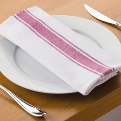 A table set with silverware and a white serviette with a rustic red stripe