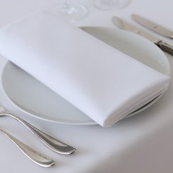 A white table set with silverware and a white napkin